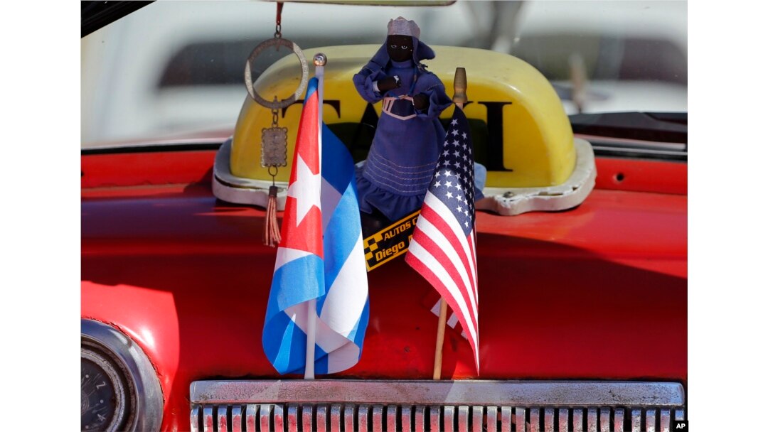 The stars and stripes and the Cuban national flag are placed together on the dashboard of a vintage American convertible in Havana, Cuba, Feb. 18, 2016.