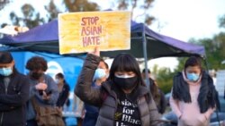 An Asian-American woman rases a sign during a peace vigil to mourn the victims of anti-Asian hate crimes at Almansor Park, Alhambra, California, U.S., March 21, 2021.