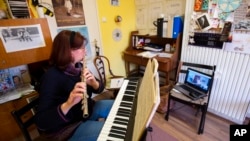 A music school teacher holds a one-to-one online flute lesson in her home, after Hungary closed schools due to coronavirus, in Nagykanizsa, southwestern Hungary, Tuesday, March 17, 2020. (Gyorgy Varga/MTI via AP)