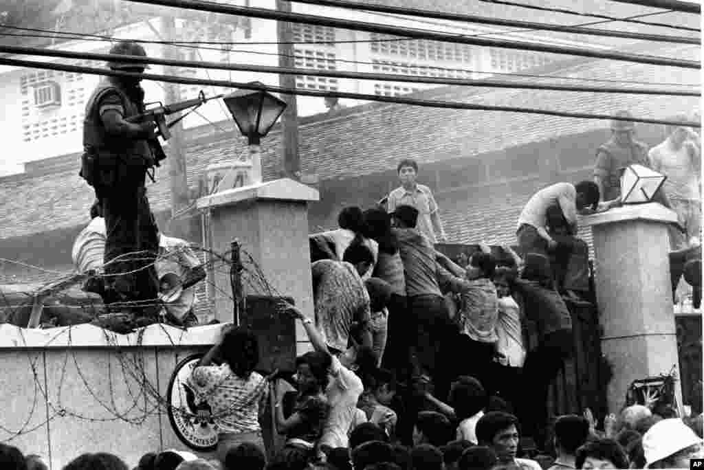 Đám đông người Việt hỗn loạn leo qua bức tường của Đại sứ quán Mỹ ở Sài Gòn, cố gắng để đến khu vực&nbsp;đón máy bay trực thăng, ngay trước khi chiến tranh Việt Nam kết thúc, ngày 29/4/1975. (AP Photo/Neal Ulevich)