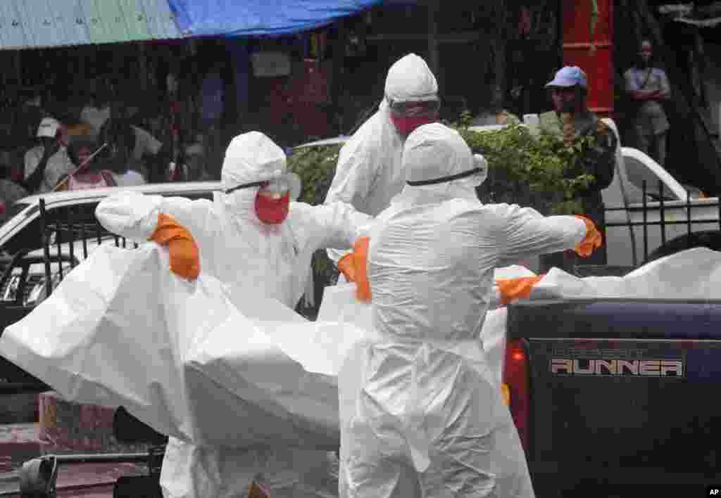 Petugas kesehatan mengangkat jenazah seseorang yang diduga mati karena virus Ebola ke dalam truk di sebuah jalan yang ramai di Monrovia, Liberia (2/9). (AP Photo/Abbas Dulleh)