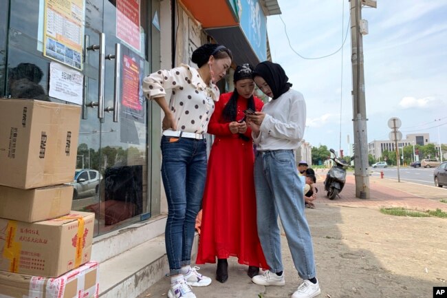 In this June 5, 2019, photo, women from the the Hui Muslim ethnic minority from a nearby neighborhood gather outside a shop near an OFILM factory in Nanchang in eastern China's Jiangxi province. (AP Photo/Ng Han Guan)