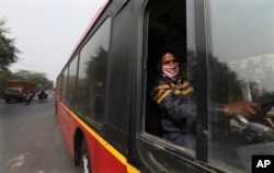 FILE - Delhi Transport Corporation bus driver Surinder Singh, 47, wearing a face mask as precaution against coronavirus and pollution drives in New Delhi, India, Wednesday, Nov. 25, 2020. (AP Photo/Manish Swarup)