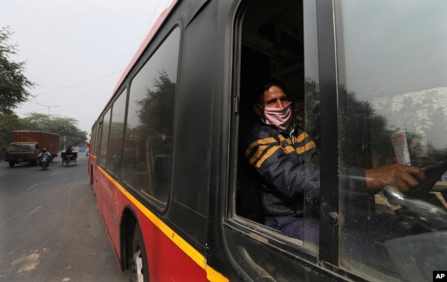 FILE - Delhi Transport Corporation bus driver Surinder Singh, 47, wearing a face mask as precaution against coronavirus and pollution drives in New Delhi, India, Wednesday, Nov. 25, 2020. (AP Photo/Manish Swarup)