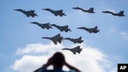 FILE - A man watches Russian military jets performing in Alabino, outside Moscow, Russia, Aug. 12, 2017. Russia's planned ‘Zapad 2017’ exercises on the border with Baltic states and Poland are viewed with suspicion by NATO alliance members. 