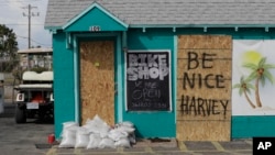 FILE - A sign reading "Be Nice Harvey" was left behind on a boarded up business, Aug. 24, 2017, in Port Aransas, Texas.