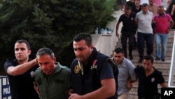FILE - Members of Turkey's armed forces are escorted by police at the court house in Mugla, a Mediterrenean city of Turkey, for their suspected involvement in an attempted July 2016 coup. 