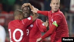 Canada's Simeon Jackson (L) and Kevin McKenna (R) celebrate with teammate Tosaint Ricketts after he scored on Cuba in the first half of their 2014 FIFA World Cup qualifying soccer match in Toronto, October 12, 2012. 