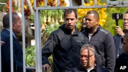 Venezuelan opposition leader Juan Guaido stands near a gate at the home of one of his key aides, lawyer Roberto Marrero, in Caracas, Venezuela, March 21, 2019. 