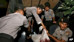Polisi di Medan mengangkat jenazah migran ilegal dari Burma yang tewas dalam bentrokan, Jumat (5/4). (AP/Binsar Bakkara)