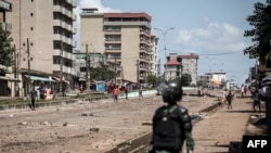 Un officier de police regarde les manifestants, alors qu'ils continuent de lancer des pierres et de bloquer les routes lors de manifestations de masse après la publication des résultats préliminaires à Conakry le 23 octobre 2020.