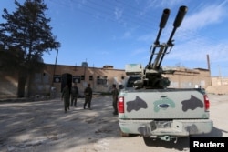 Fighters from the Democratic Forces of Syria walk outside a prison which, according to them, belonged to Islamic State fighters, in al-Shadadi town, in Hasaka province, Syria Feb. 26, 2016.