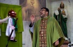 Pendeta Katolik Carlos Cardona menyampaikan homilinya saat Misa, di samping salah satu boneka Santo Yudas Thaddeus, di gereja Santo Yudas Thaddeus di Huixquilucan, Mexico City, Minggu, 27 Juni 2021. (Foto: AP/Marco Ugarte)