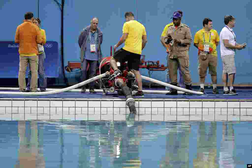 Technical officers and staff members of the Lenk Aquatic Center watch as the process of draining the pool where the 2016 Summer Olympics synchronized swimming competition is to be held in Rio de Janeiro, Brazil, started Aug. 13, 2016. 