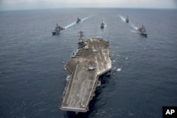 In this Friday, April 28, 2017 photo released by the U.S. Navy, the Nimitz-class aircraft carrier USS Carl Vinson (CVN 70) leads the Japan Maritime Self-Defense Force destroyers JS Ashigara (DDG 178), top left, JS Samidare (DD 106), second left, the Arleigh Burke-class guided-missile destroyers USS Michael Murphy (DDG 112), center, USS Wayne E. Meyer (DDG 108), second right, and the Ticonderoga-class guided-missile cruiser USS Lake Champlain (CG 57), right, during a transit the Philippine Sea.