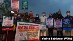 Perwakilan Orang Muda Katolik, Pandu (baju putih berkalung salib) membagikan takjil pada warga muslim di Solo Baru, Jalur perbatasan kota Solo dan Kabupaten Sukoharjo, Jumat (7/5). (Foto: VOA/ Yudha Satriawan)