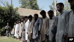 FILE - Arrested Islamic State fighters stand outside Afghan police headquarters in Nangarhar, Afghanistan.