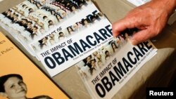 A Tea Party member reaches for a pamphlet titled "The Impact of Obamacare", at a Tea Party Rally in Littleton, New Hampshire, Oct. 27, 2012