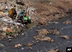 FILE - Workers dump effluent from pit latrines from the Korogocho slum of Nairobi, Kenya into a local water course.