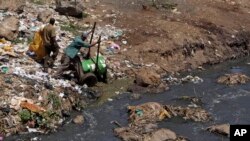 FILE - Workers dump effluent from pit latrines from the Korogocho slum of Nairobi, Kenya into a local water course.