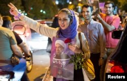 FILE - A woman holds a poster of Iranian President Hassan Rouhani during a campaign rally in Tehran, Iran, May 17, 2017.