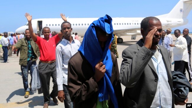 FILE- Deported Somali nationals gesture as they arrive at the airport in Somalia's capital of Mogadishu, April 9, 2014. Sixty-eight Somalis arrived in Magodishu Friday, having been deported by U.S. immigration authorities.