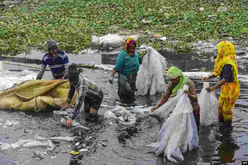 Workers clean plastic bags used to carry industrial chemicals in the Buriganga river in Dhaka, Bangladesh.