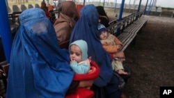 Afghan refugee women sit with their babies as they wait with others to be repatriated to Afghanistan, at the United Nations High Commissioner for Refugees (UNHCR) office on the outskirts of Peshawar, Feb. 2, 2015.