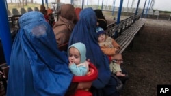 FILE - Afghan refugee women sit with their babies as they wait with others to be repatriated to Afghanistan, at the United Nations High Commissioner for Refugees (UNHCR) office on the outskirts of Peshawar, Feb. 2, 2015.