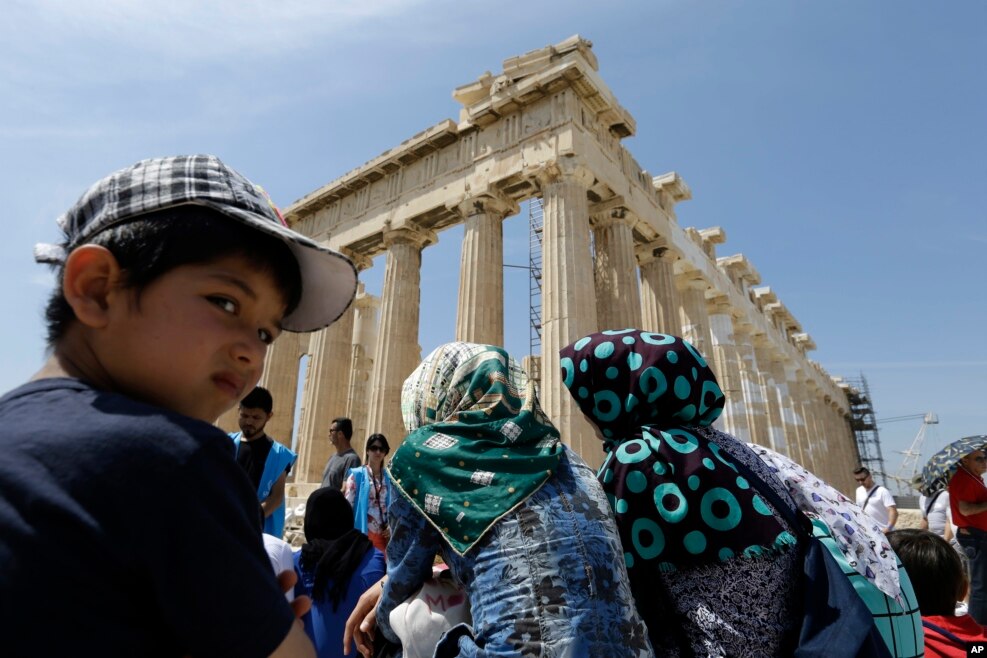 Young Afghans trapped in Greece sit in front of the 2,500-year-old Parthenon temple on the Athenian Acropolis.