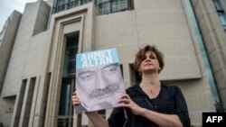 A journalist poses with a portrait of Turkish journalist Ahmet Altan, June 19, 2017, in front of the Istanbul courthouse, where his trial is to take place. 