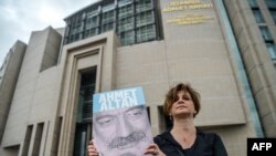 A journalist poses with a portrait of Turkish journalist Ahmet Altan, June 19, 2017, in front of the Istanbul courthouse, where his trial is to take place. 一个记者2017年6月19日在伊斯坦布尔法院外拿着受审记者亚梅特·艾坦的照片。