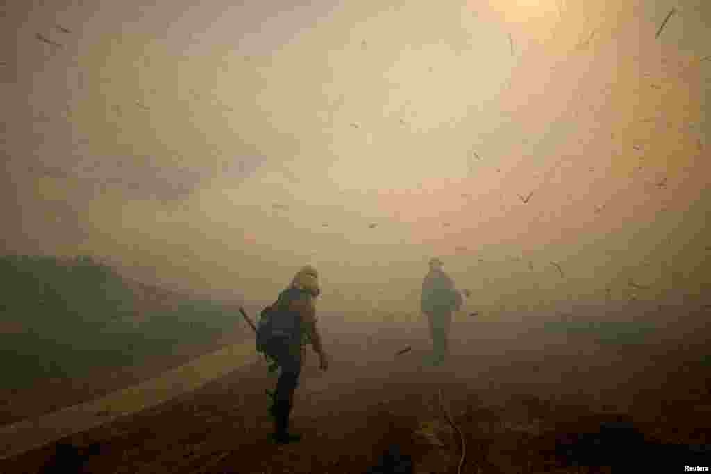 Firefighters face strong winds as they head up a hillside to battle a wind-driven wildfire near Irvine, California, Oct. 26, 2020.