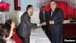 Tajikistan's President Imomali Rakhmon (R) receives his ballot from an electoral official during the presidential election in Dushanbe, in this Nov. 6, 2013 handout photograph provided by Press Service of presidential administration of Tajikistan. 