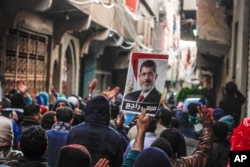 ບັນດາຜູ້ສະໜັບສະໜູນ ອະດີດປະທານາທິບໍດີ ຜູ້ຖືກໂຄ່ນລົ້ມ ທີ່ນັບຖືສາສະໜາອິສລາມ ທ່ານ Mohamed Morsi, ຮ້ອງໂຮຄຳຂວັນ ແລະ ຊູຮູບຂອງທ່ານ Morsi ພາຍຫຼັງທີ່ພັກພະລາດອນພາບ ມູສລິມ ຮຽກຮ້ອງໃຫ້ບັນດາຜູ້ສະໜັບສະໜູນຂອງຕົນ ອອກມາເດີນຂະບວນ ເນື່ອງໃນວັນຄົບຮອບ ການລຸກຮືຂຶ້ນ ຂອງປີ 2011 ໃນນະຄອນ Cairo, ປະເທດອີຈິບ.