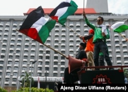 Seorang anggota organisasi buruh Indonesia memegang bendera Palestina saat melakukan aksi protes terhadap Israel di luar gedung PBB di Jakarta, 18 Mei 2021. (Foto: REUTERS/Ajeng Dinar Ulfiana)