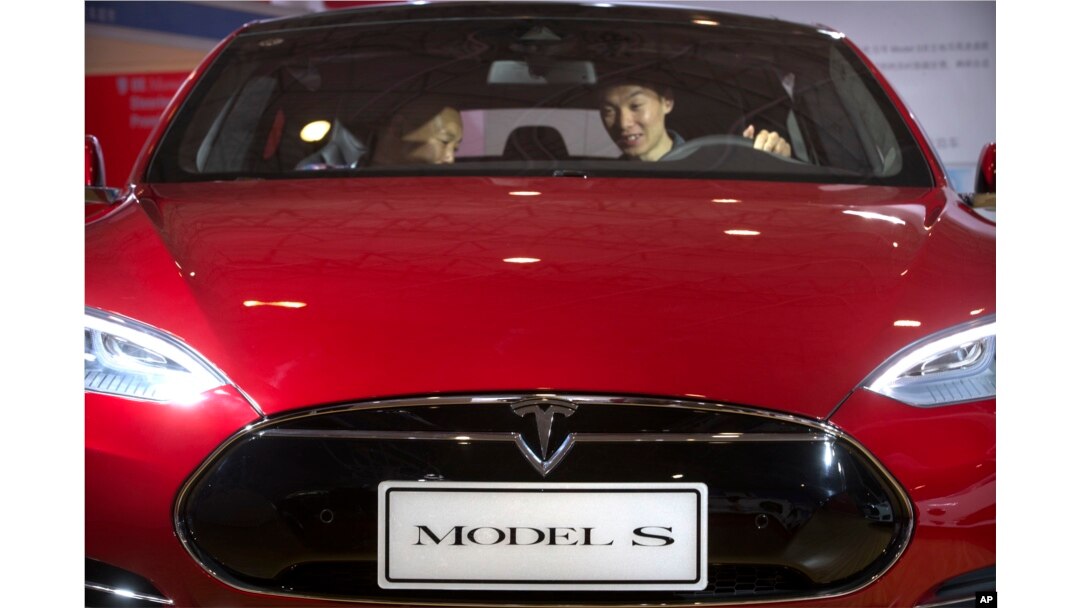 FILE - A man sits in a Tesla Model S electric car on display at a Beijing auto show, April 25, 2016. In May, a Tesla on "autopilot'' crashed into a truck that was turning, drawing attention to the limitations of self-driving technology.