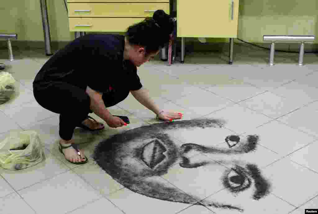 Hairdresser Svetlana Grozdanovska creates a celebrity&#39;s portrait on the floor of her salon using her clients&#39; cut hair, in Krivogastani, North Macedonia.