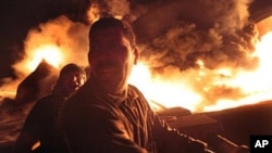 Libyan men react as the main fuel depot in Misrata burns after a bombing by pro-Gadhafi forces, May 7, 2011