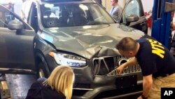 Petugas badan keselamatan transportasi AS memeriksa mobil SUV swakemudi Uber yang menabrak seorang perempuan hingga tewas di Tempe, Arizona (20/3). 