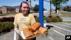 Laura Hallmark, owner of Strange Brew Coffeehouse, poses March 26, 2020 with loafs of bread she and her team made at the store in Tupelo Miss. The coffeehouse has started making bread to help with the demand during the coronavirus outbreak. (AP Photo/Juli Cortez)