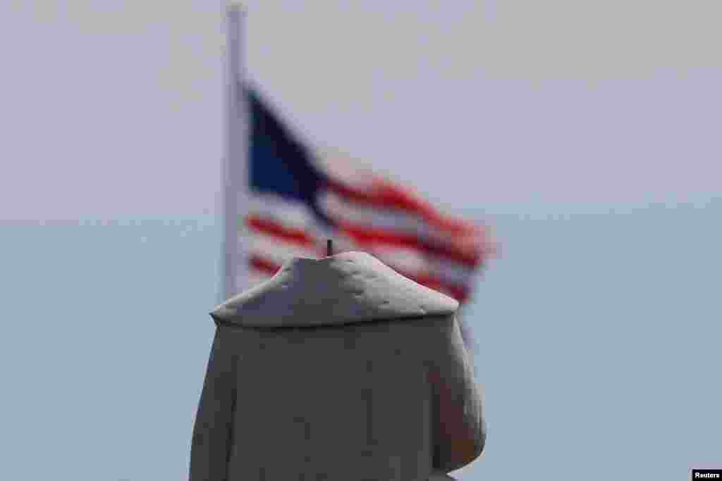 بوسٹن میں کرسٹوفر کولمبس کا بغیر سر والا مجسمہ، پس منظر میں امریکی پرچم لہراتا نظر آ رہا ہے۔