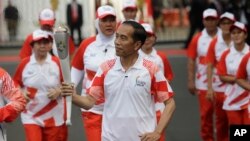 Indonesian President Joko "Jokowi" Widodo, center, holds the Asian Games torch as he runs during an independence day ceremony at Merdeka Palace in Jakarta, Indonesia, Aug. 17, 2018. 