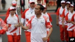 Indonesian President Joko "Jokowi" Widodo, center, holds the Asian Games torch as he runs during an independence day ceremony at Merdeka Palace in Jakarta, Indonesia, Aug. 17, 2018. Jokowi announced Indonesia would bid for the 2032 Olympic Games.