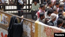 Seorang perempuan Yemen mengambil foto dari belakang pagar di Alun-Alun Taghyeer tempat para demonstran anti pemerintahan. (Foto: Reuters)