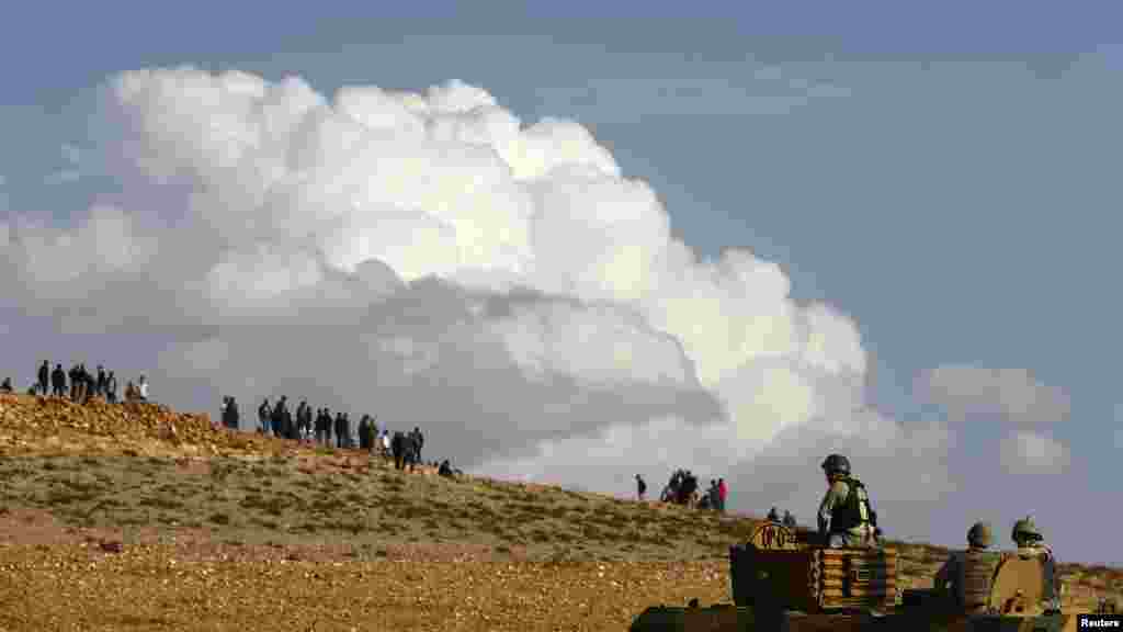 Turkish military look toward observers as they try to clear a hill near the Mursitpinar crossing on the Turkish-Syrian border, Oct. 26, 2014.