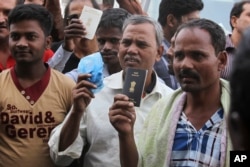 FILE - Foreign workers hold their passports as they gather outside a labour office, after missing a deadline to correct their visa status, in Riyadh, Nov. 4, 2013