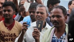 FILE - Foreign workers hold their passports as they gather outside a labour office, after missing a deadline to correct their visa status, in Riyadh, Nov. 4, 2013