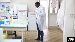 Dr. Mombo dons his white coat as he prepares to analyse samples at the Franceville International Centre of Medical Research (CIRMF) is seen on June 12, 2018 in Franceville.