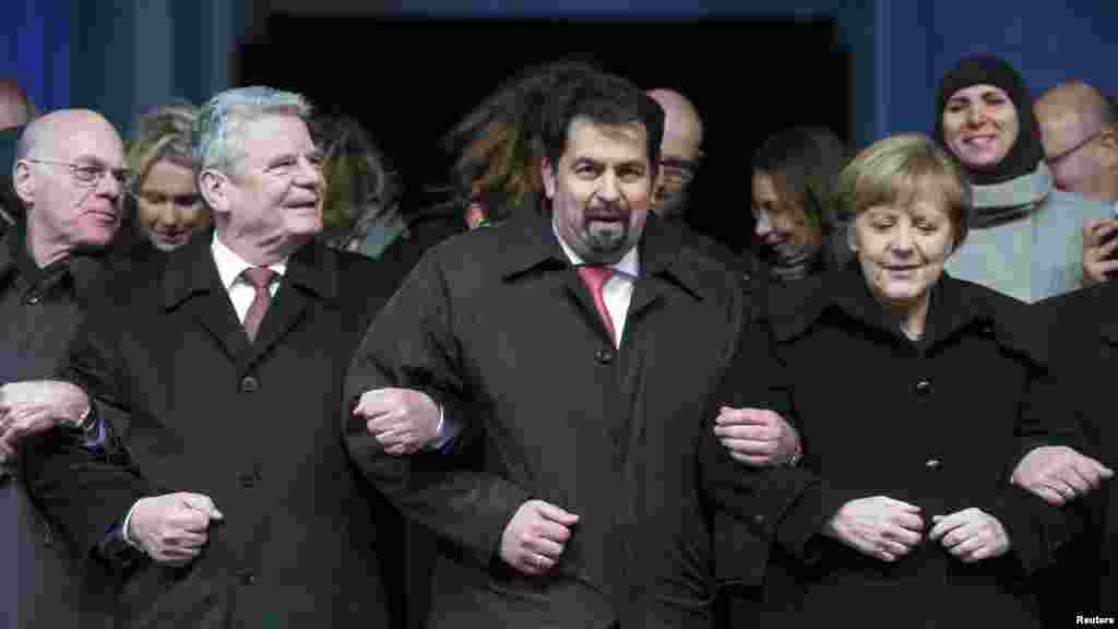 Le président du Bundestag, Norbert Lammert, le président allemand Joachim Gauck, le président du Conseil central des musulmans en Allemagne Aiman Mazyek et la chancelière allemande Angela Merkel, mrachent, bras dans le bras, lors d&#39;une veillée organisée pour les victimes de la fusillade.